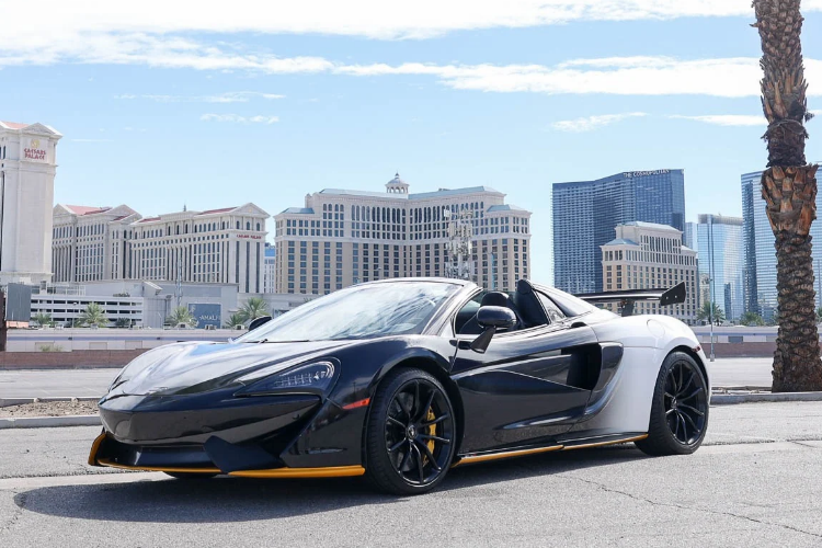 Black and white McLaren 570S Spider with yellow accents parked in Las Vegas near Caesars Palace.