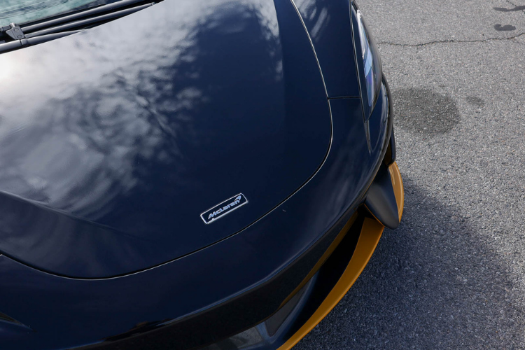 Close-up of the McLaren 570S Spider hood featuring the McLaren emblem and glossy black wrap.