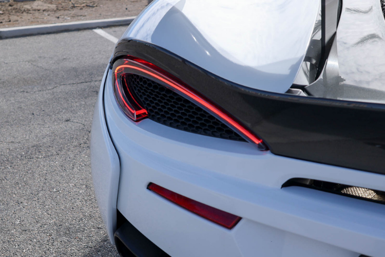 Close-up of the McLaren 570S Spider rear LED taillight, white bodywork, and carbon fiber detailing.