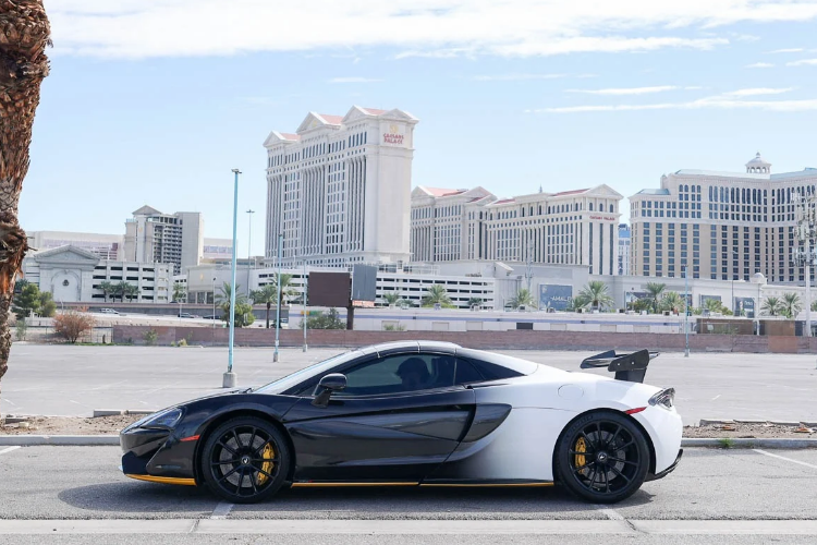 Side profile of a black and white McLaren 570S Spider with yellow accents and custom rear wing in Las Vegas.