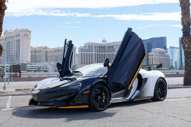 McLaren 570S Spider with butterfly doors raised, showing off its custom black and white wrap near the Las Vegas Strip.
