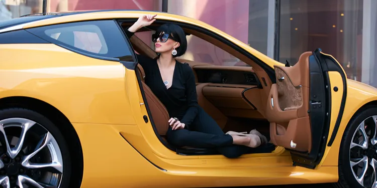 Yellow exotic wports car with fashionable woman inside.