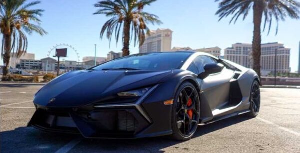 Black luxury sports car with palm trees and Las Vegas strip.