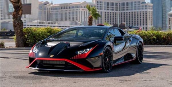 Black exotic car with red detailing against a backdrop of the Las Vegas Strip.